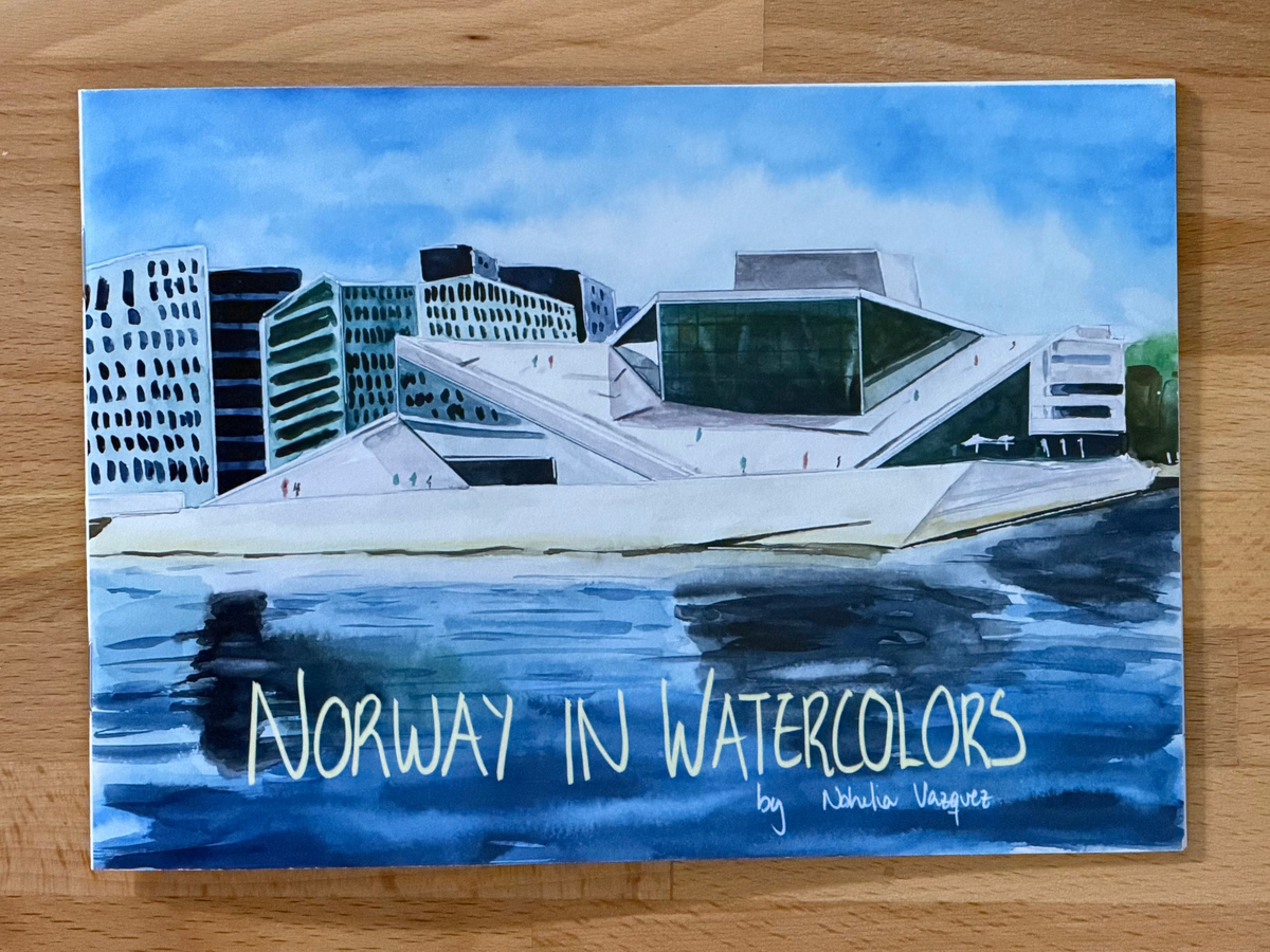 A watercolor painting of the Oslo Opera House and surrounding buildings, with the title 'Norway in Watercolors' and the artist name 'Nohelia Vazquez' written at the bottom, displayed on a wooden surface.